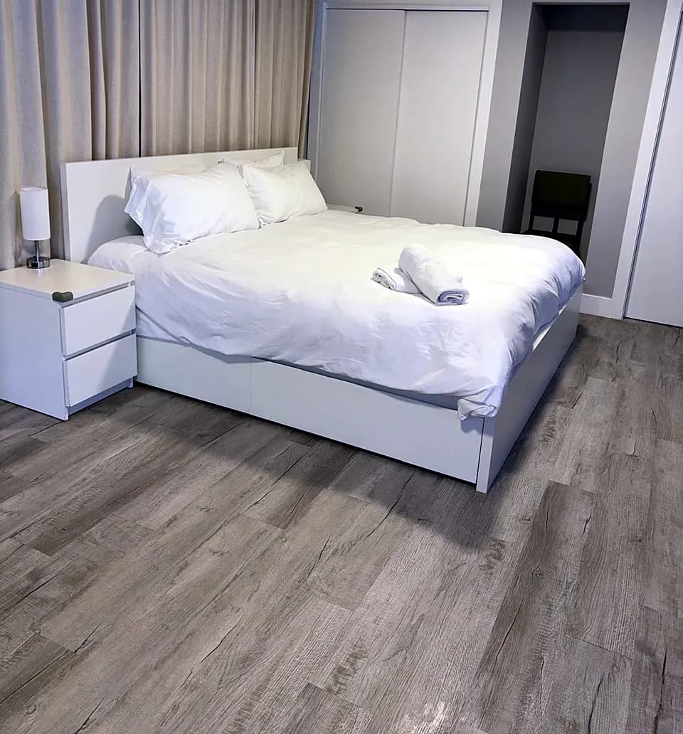 Bedroom with white bedding and gray floors after cleaning