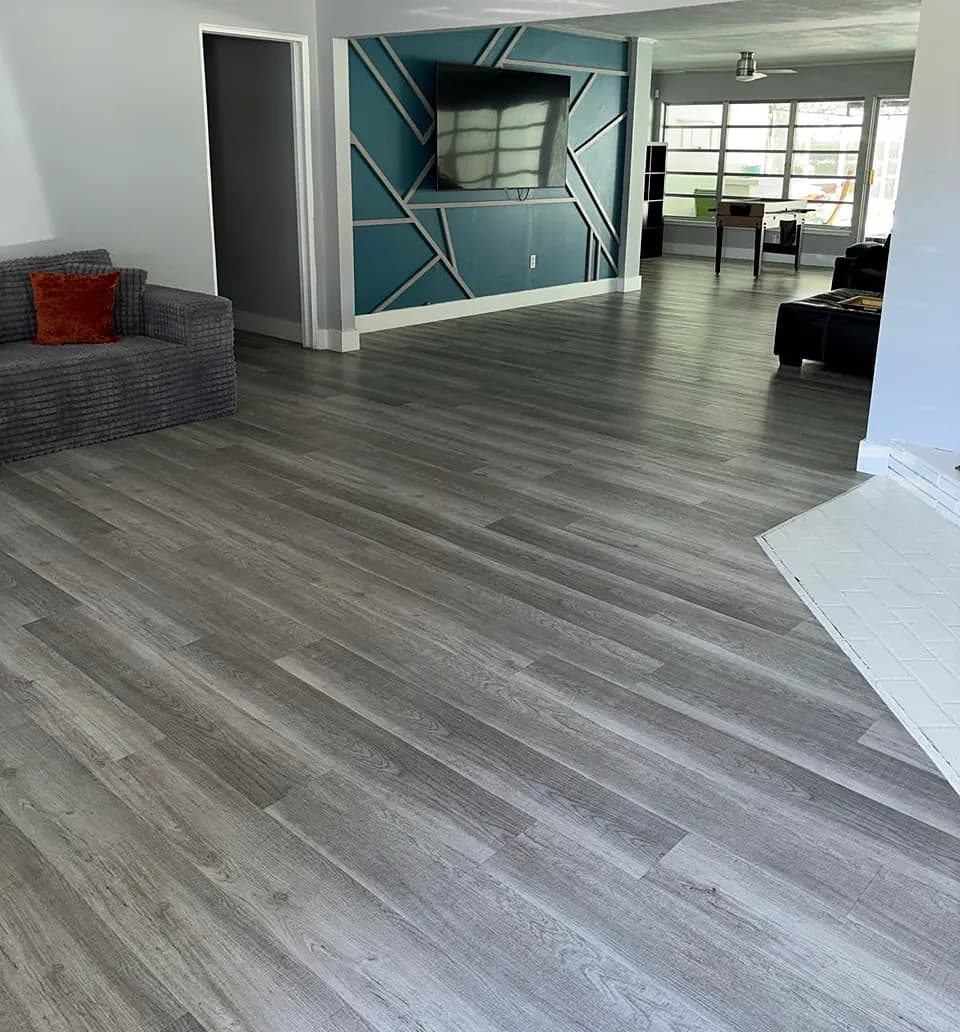 Clean, open living room with gray plank flooring and natural light