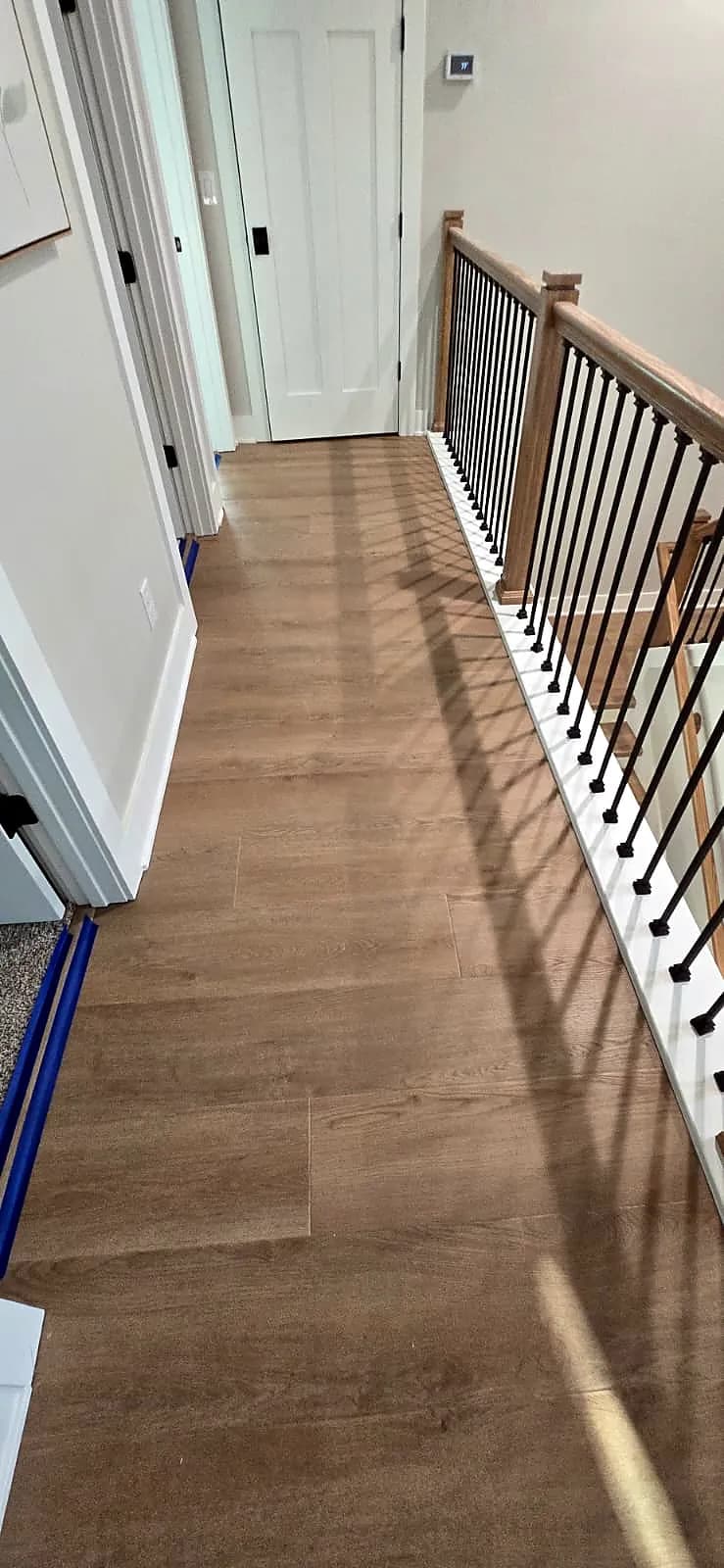 Upstairs hallway with plank flooring and iron balusters